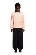 Person wearing a light Boy London pink tie-dye sweatshirt and black pants on a white background