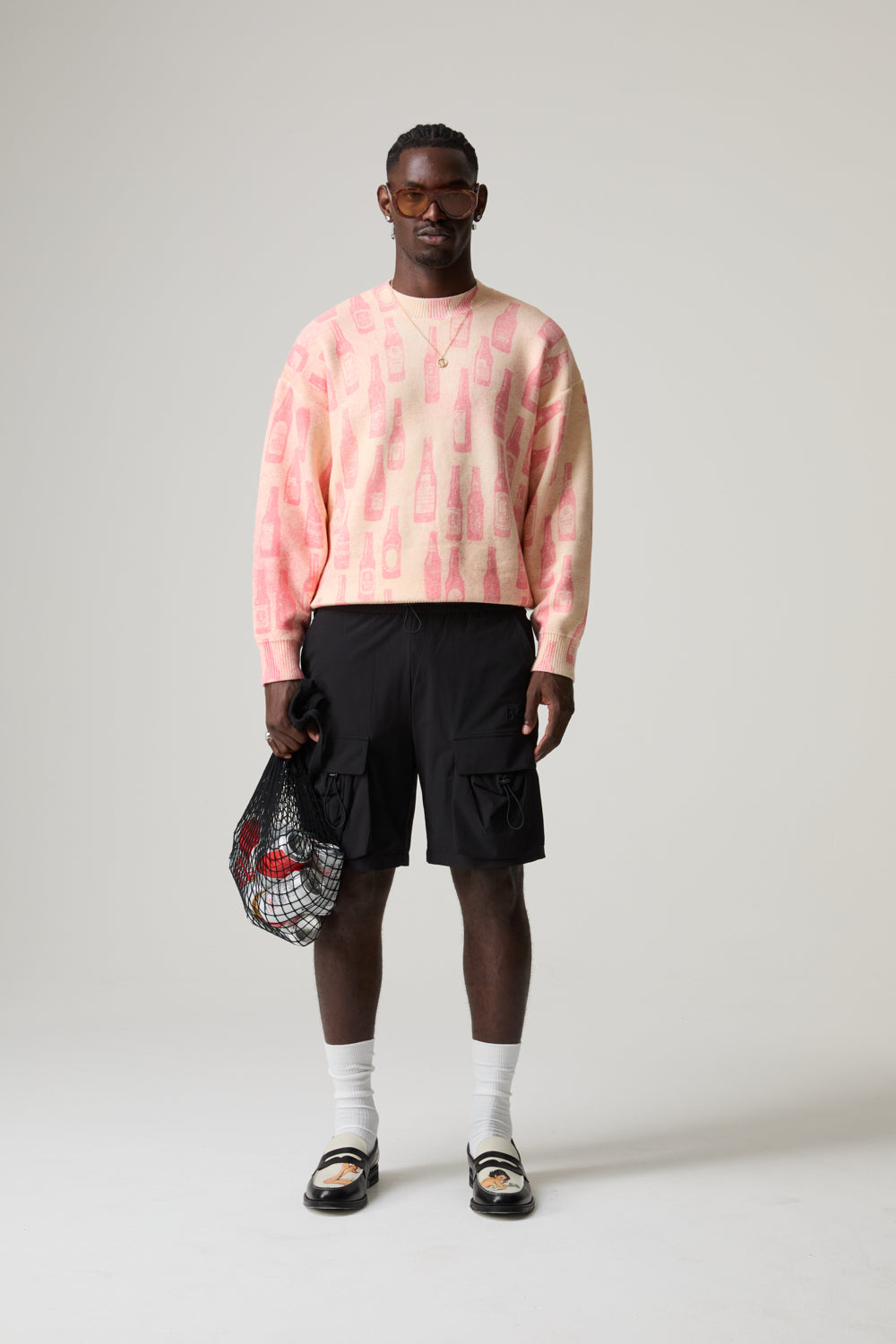 Model wearing a pink BOY LONDON sweatshirt, black shorts, white socks, and sandals on a plain background