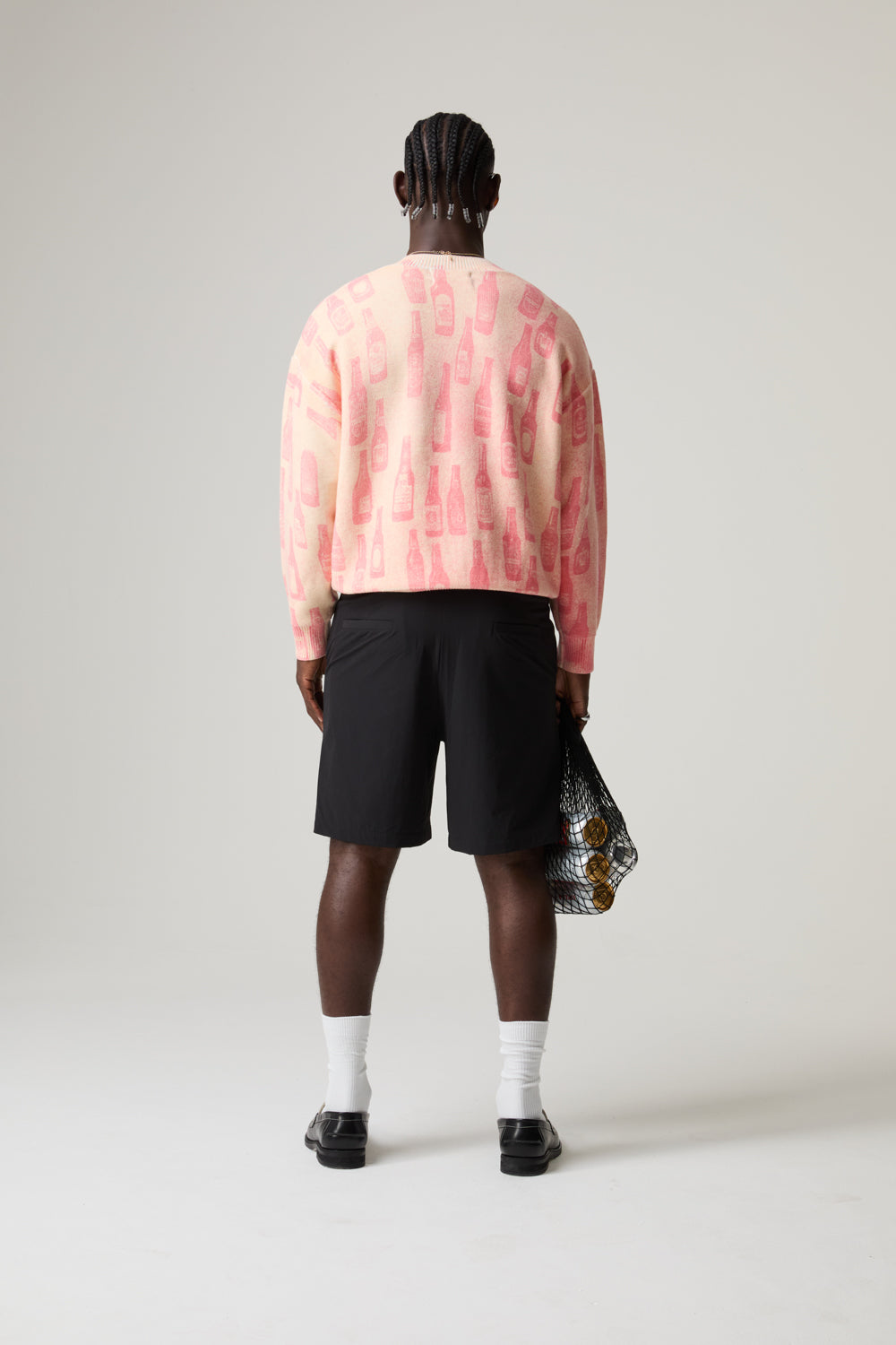 Model wearing a pink BOY LONDON sweater, black shorts, and white socks with a neutral background
