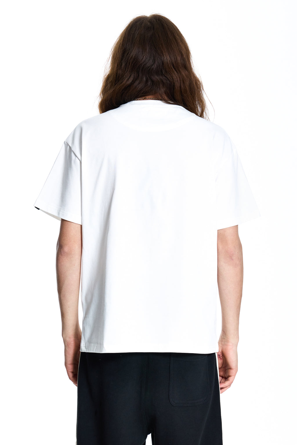 Person wearing a white Boy London T-shirt with graphic design and black pants with white stripes on a white background