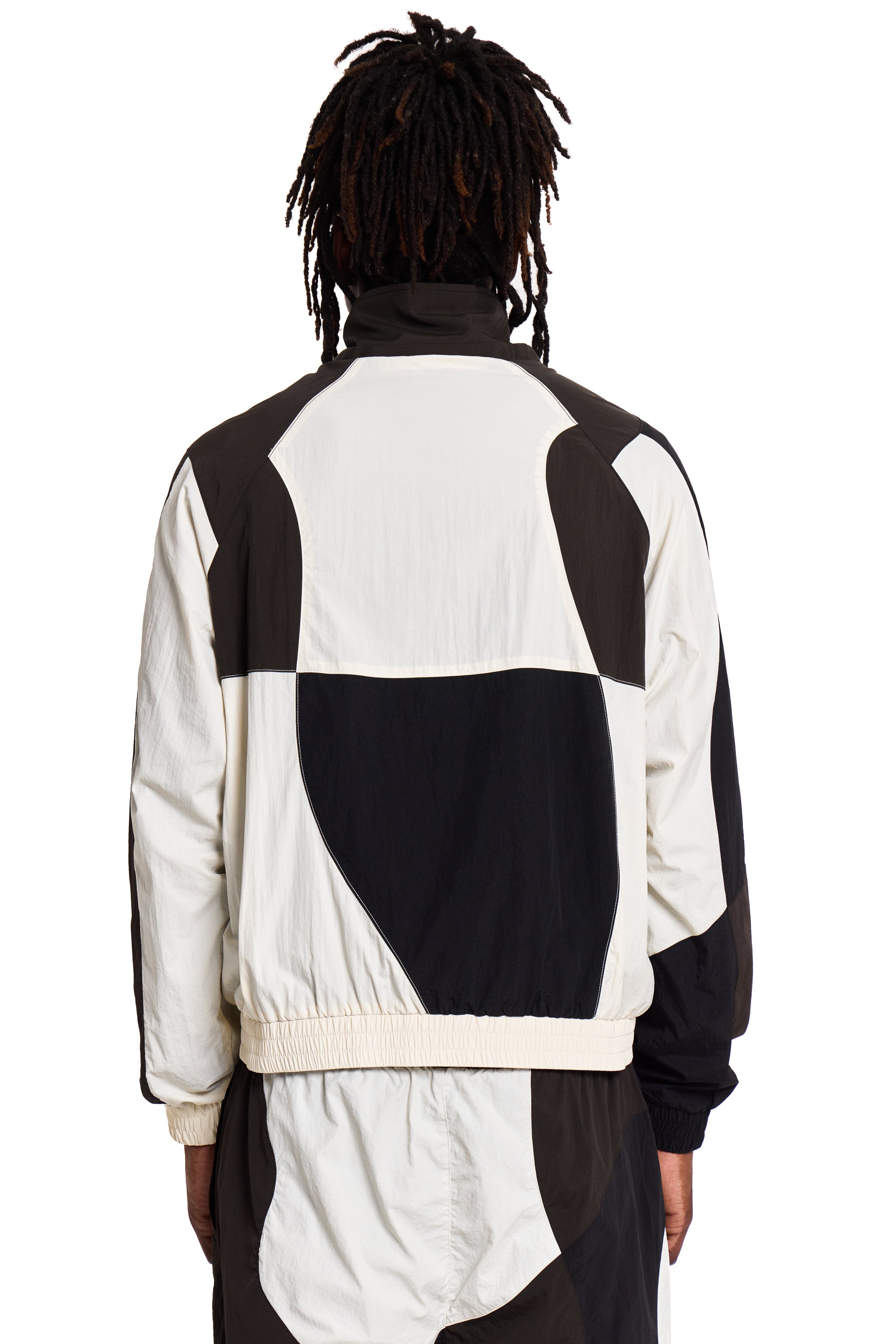 Person wearing a black and white Boy London jacket with geometric pattern on a white background