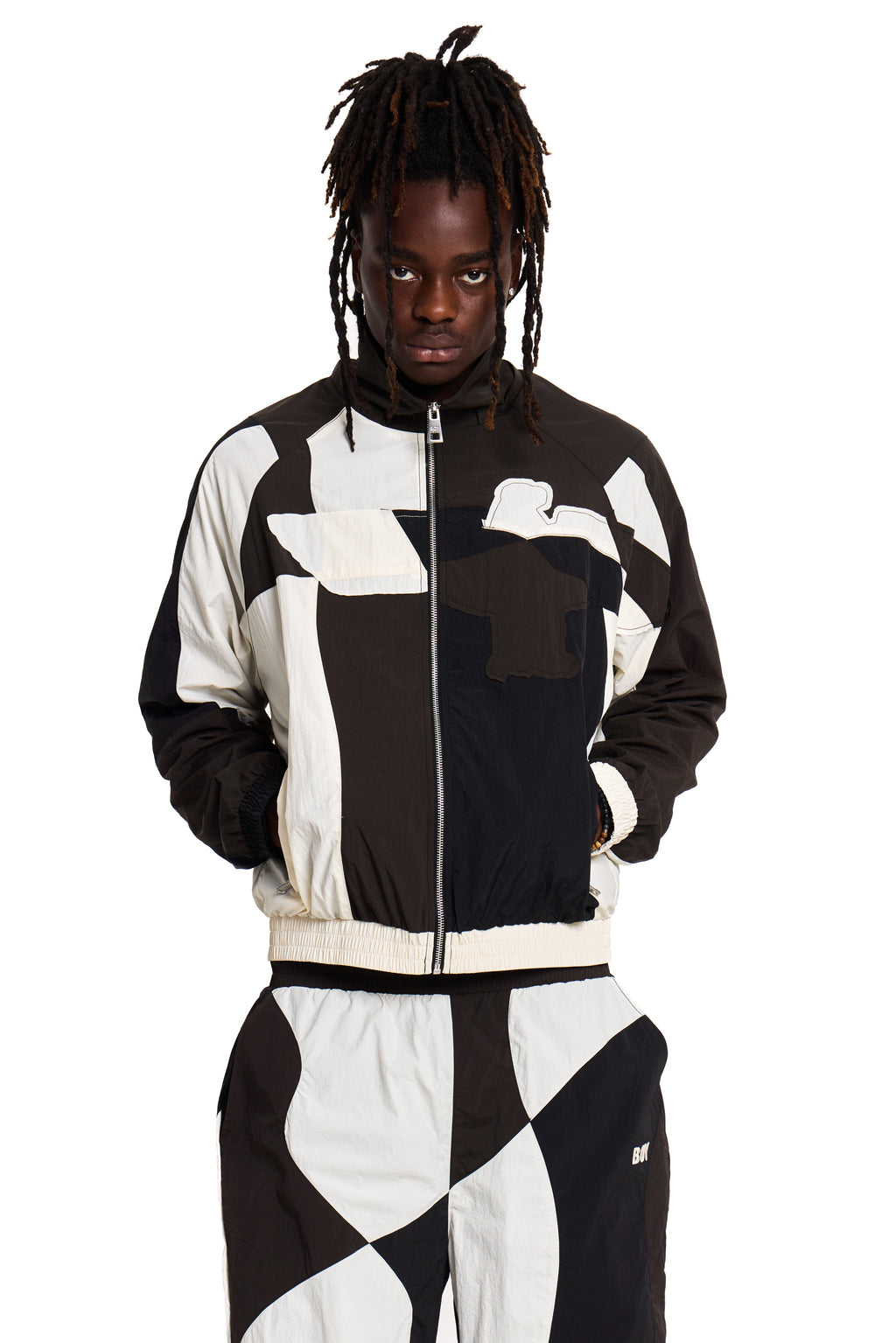 Person wearing a black and white Boy london checkered jacket and pants on a white background