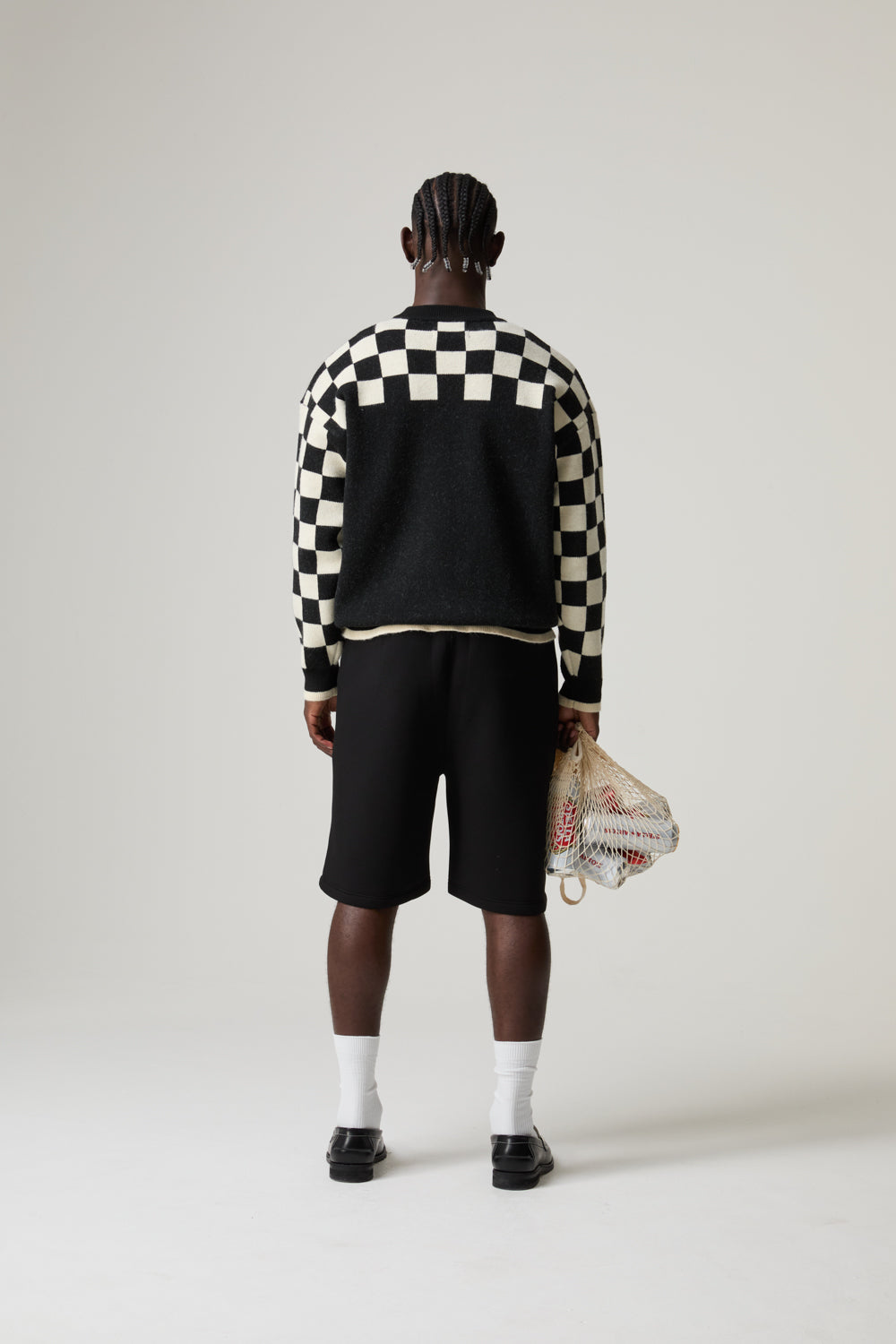 Model wearing a black and white BOY LONDON checkered jacket with a plain background