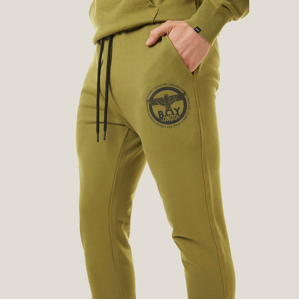 Model wearing green BOY London tracksuit with brand logo on a white background