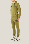 Model wearing a green BOY London tracksuit with a logo on a light gray background